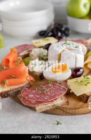 Platte mit kaltgeschnittenen Sandwiches auf einem Holzbrett auf einem Küchentisch Stockfoto