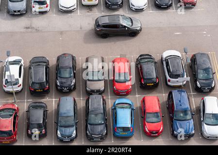 Autos auf einem Parkplatz geparkt, von oben gesehen. Markierte Parkbuchten, alle von einem geparkten Auto. Voll ausgestattete Parkboxen. Fahrer sucht nach Platz Stockfoto
