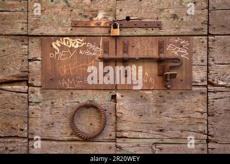 Rostiger Türriegel, Schiebeschalter und Vorhängeschlösser an der alten Holztür, Trastevere, Rom, Italien Stockfoto