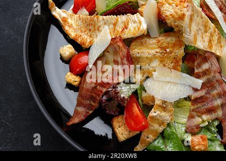 Köstlicher Caesar Salat garniert mit knusprigem Speck, gegrilltem Hähnchen und Parmesan Käse Stockfoto