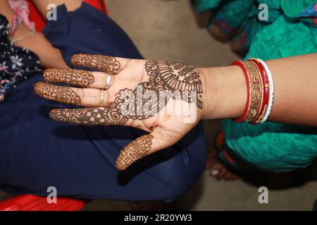 Indisches Teenager-Mädchen, das Heena Tatoo auf die Hand einer Frau aufträgt Stockfoto