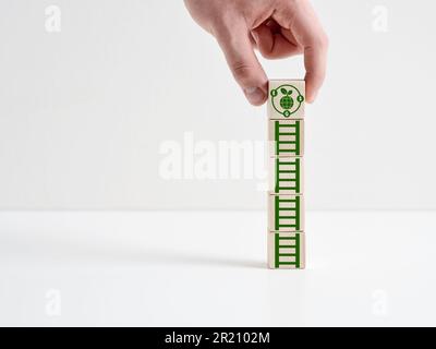 ESG-Konzept für umweltpolitische und soziale Governance und nachhaltige Entwicklung. Die Hand legt einen Holzwürfel mit dem ESG-Symbol auf die Würfel mit dem Leitersymbol. Stockfoto