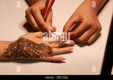 Indisches Teenager-Mädchen, das Heena Tatoo auf die Hand einer Frau aufträgt Stockfoto