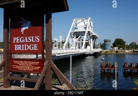 Foto der Pegasus-Brücke in der Normandie. Die Pegasus Bridge, ursprünglich Benouville Bridge genannt, ist eine Straße, die den Caen-Kanal zwischen Caen und Ouistreham in der Normandie kreuzt. Die ursprüngliche Brücke, die 1934 erbaut wurde, ist heute ein Kriegsdenkmal und das Herzstück des Memorial Pegasus Museums im nahe gelegenen Ranville. Es wurde 1994 durch ein modernes Design ersetzt, das, wie die alte, eine Bascule Bridge ist. Stockfoto