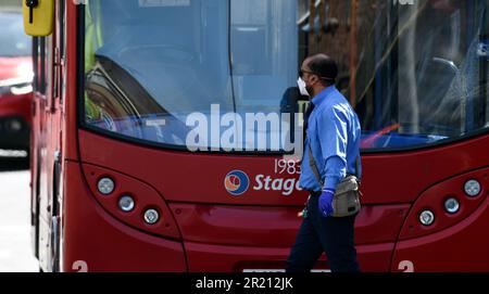 Foto eines Londoner Busfahrers während der Covid-19-Pandemie. Man sieht ihn mit einer Gesichtsmaske als seine einzige persönliche Schutzausrüstung. Stockfoto