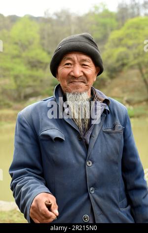 Last of the Pula - einer der ältesten Bewohner des Dorfes Pi Po liest Rituale, die in einer Sprache geschrieben wurden, die bald zu einer vergessenen Sprache des Pula werden könnte, die in dem Dorf östlich von Kaiyuan in der autonomen Präfektur Hani und Yi Honghe, Provinz Yunnan, SW China - das Dorf ist die Heimat der Pula, einer Unterminderheit der Yi- oder Lolo-Bevölkerung, einer ethnischen Gruppe in China, Vietnam und Thailand. Mit 8 Millionen sind sie die siebtgrößte der 55 ethnischen Minderheiten. Stockfoto