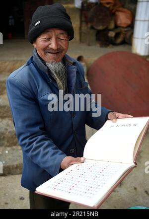 Last of the Pula - einer der ältesten Bewohner des Dorfes Pi Po liest Rituale, die in einer Sprache geschrieben wurden, die bald zu einer vergessenen Sprache des Pula werden könnte, die in dem Dorf östlich von Kaiyuan in der autonomen Präfektur Hani und Yi Honghe, Provinz Yunnan, SW China - das Dorf ist die Heimat der Pula, einer Unterminderheit der Yi- oder Lolo-Bevölkerung, einer ethnischen Gruppe in China, Vietnam und Thailand. Mit 8 Millionen sind sie die siebtgrößte der 55 ethnischen Minderheiten. Stockfoto