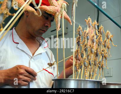 Peking, China - Snack Street in Wangfujing - der Wangfujing Nachtmarkt bietet eine Auswahl an exotischen Street Food in der Snack Street. Frittierte Insekten, Skorpione und Meeresbewohner sind ebenso zu finden wie andere Tiere und Tierteile, die normalerweise im Westen nicht als Nahrung konsumiert werden. Doch während diese exotischen Snacks zu finden sind, machen andere gängigere Lebensmittel wie Chuanr (Fleischkebabs, die häufig aus Lamm hergestellt werden) und Desserts wie Tang hu lu oder kandierte Früchte den Großteil der auf der Straße verkauften Lebensmittel aus. Stockfoto