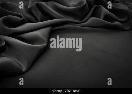 Struktur aus Satin oder Seide in schwarzer Farbe. Textil. Stoffhintergrund mit Falten und Wellen Stockfoto