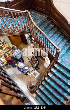 Hölzerne Treppe im georgianischen Stil mit blauem Teppich mit Blumenmuster in der William Morris Gallery, Walthamstow, London, Großbritannien Stockfoto