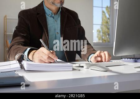 Geschäftsmann, Buchhalter oder Wirtschaftsprüfer, der im Büro arbeitet, Computer verwendet und Papierkram erledigt Stockfoto