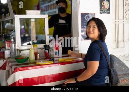 Mexico City, Mexiko, 07. Mai 2023: Asiatisches Mädchen isst Taco in einer Taqueria Stockfoto