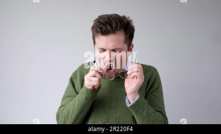 Der europäische junge Mann reinigt seine Gläser von Dreck Stockfoto