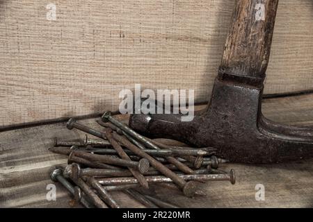 Nahaufnahme des Hammers mit Nägeln auf Holz mit schwarzem Hintergrund mit reduzierter Lebendigkeit, schäbig, alt, antik, altmodisch Stockfoto