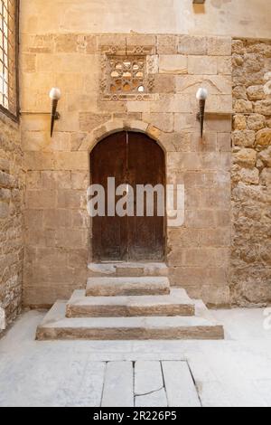 Alte Backsteinmauer mit einer gewölbten Holztür und alten Treppen Stockfoto