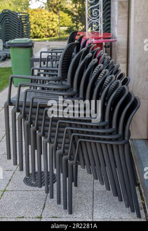 Ein Stapel grauer Gartenstühle neben einer Wand des Hotels Stockfoto