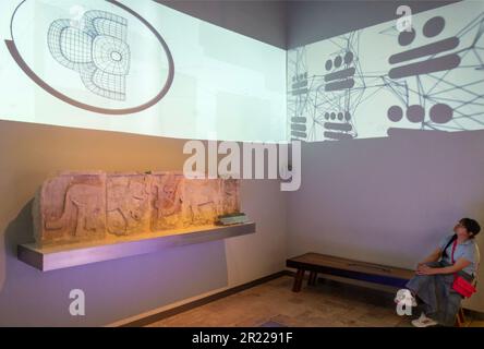 one woman watching designs on a wall at the Grand Museum of the Mayan World in Merida Yucatan Mexico Stock Photo