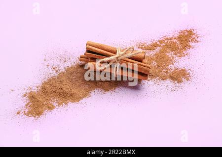 Ein Haufen Zimtstäbchen und Puder auf farbigem Hintergrund Stockfoto