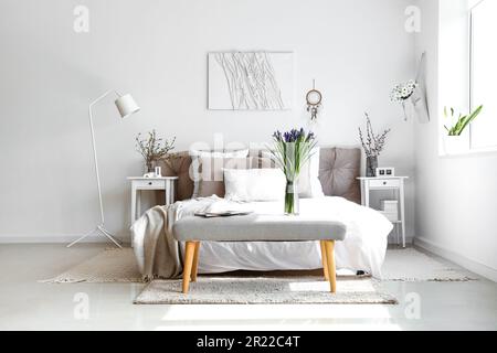 Helles Schlafzimmer mit wunderschönen Irisblumen auf der Nachtbank Stockfoto