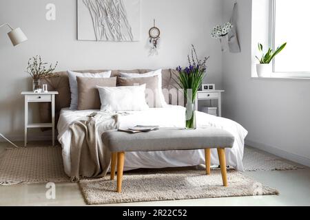 Helles Schlafzimmer mit wunderschönen Irisblumen auf der Nachtbank Stockfoto