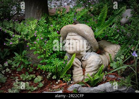 Savannah, Georgia, USA - 10. März 2022: Skulptur für kleine Jungen inmitten eines üppigen, altmodischen Gartens Stockfoto