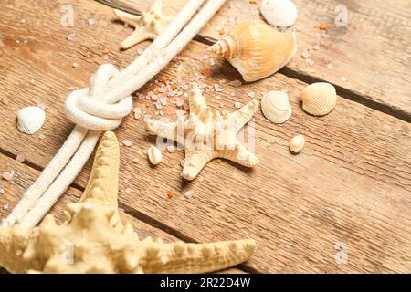 Muscheln und Seesterne mit Seil auf braunem Holzhintergrund Stockfoto