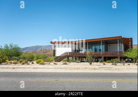 Borrego Springs, CA, USA - 24. April 2023: Öffentliches Bibliotheksgebäude im modernen Architekturstil unter blauem Himmel, auf sandigem Wüstenboden mit grünem Busch gelegen Stockfoto