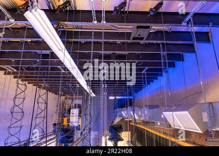 Theaterbühne mit Theaterausstattung, Beleuchtung, Stützen und Ketten. Foto aus einer erhöhten Position mit Blick über die Halterung. Stockfoto