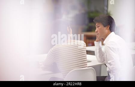 Ich komme gleich zur Sache. Rückansicht zweier asiatischer Geschäftskollegen, die über die Arbeit im Büro diskutieren. Stockfoto