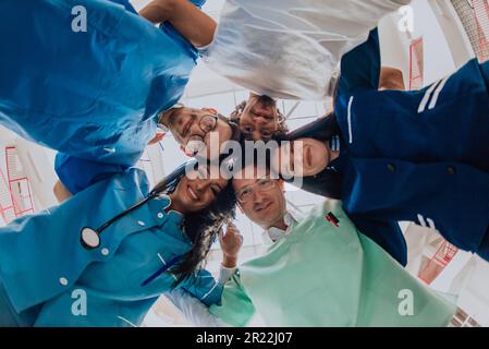 Gruppe von Ärzten eine medizinische Krankenschwester und ein Chirurg werden in einer herzlichen Umarmung gefangen und zeigen ihre Einheit, Teamarbeit und tiefe Verbindung in der Stockfoto