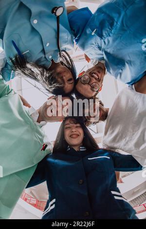 Gruppe von Ärzten eine medizinische Krankenschwester und ein Chirurg werden in einer herzlichen Umarmung gefangen und zeigen ihre Einheit, Teamarbeit und tiefe Verbindung in der Stockfoto