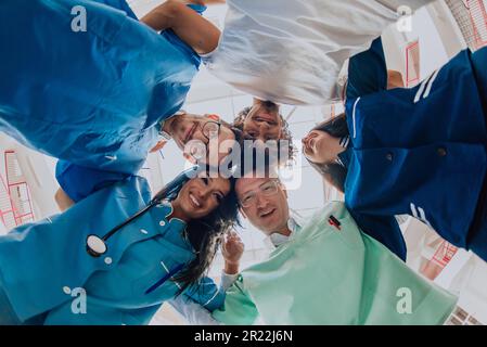 Gruppe von Ärzten eine medizinische Krankenschwester und ein Chirurg werden in einer herzlichen Umarmung gefangen und zeigen ihre Einheit, Teamarbeit und tiefe Verbindung in der Stockfoto