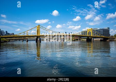 Ein blauer Himmel mit flauschigen Wolken über dem Allegheny River in Pittsburgh, Pennsylvania, mit Blick auf die gelbe Rachel Carson Bridge. Stockfoto