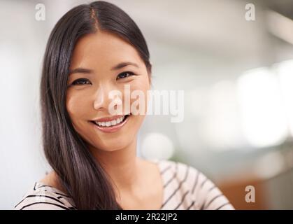 Sie ist optimistisch über ihre Zukunft im Unternehmen. Eine attraktive junge asiatische Geschäftsfrau, die in die Kamera schaut. Stockfoto