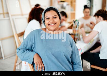 Ich bin am glücklichsten, wenn ich mit meinen Freunden zusammen bin. Verkürztes Porträt einer attraktiven jungen Frau, die mit ihren Freunden während eines Kunstkurses im Studio sitzt. Stockfoto