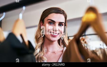 Ich werde nie aufhören, das zu tun, was ich am besten kann. Eine Designerin, die Kleidung auf einem Geländer in ihrer Werkstatt ansieht. Stockfoto