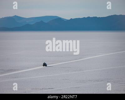 Aufregende Offroad-Tour auf Boliviens faszinierendem Salar de Uyuni. Ein fesselndes Foto zeigt ein Geländewagen, das die weltweit größten Salzebenen erkundet. Stockfoto