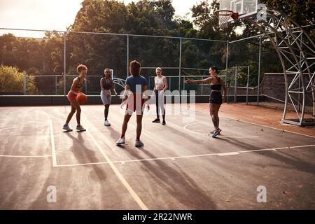 Ich versuche, so viele Punkte wie möglich zu bekommen. Eine vielfältige Gruppe von Sportlerinnen, die tagsüber gemeinsam ein Wettkampfspiel mit Basketball spielen. Stockfoto