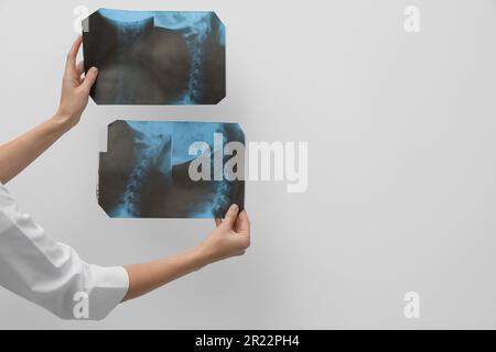Arzt untersucht Hals-MRT-Bilder auf hellgrauem Hintergrund, Nahaufnahme. Platz für Text Stockfoto