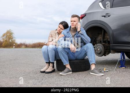 Ein junger Mann ruft beim Autoservice an. Reifenpanne Stockfoto