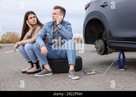 Ein junger Mann ruft beim Autoservice an. Reifenpanne Stockfoto