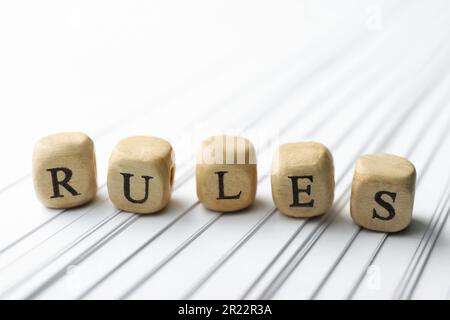 Wortregeln aus Holzwürfeln mit Briefen und Büchern auf weißem Papier Stockfoto