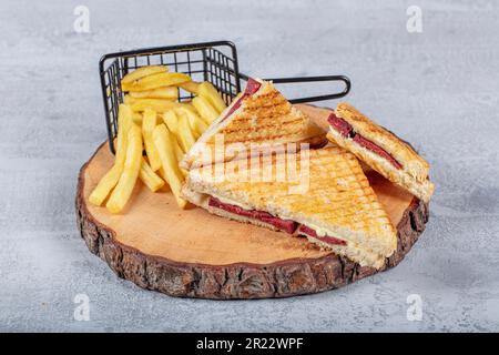 Türkischer Toast, gemischter Toast mit Cheddar-Käse, Wurst und Schinken, mit Bratkartoffeln (türkischer Name; Karisik tost) Stockfoto