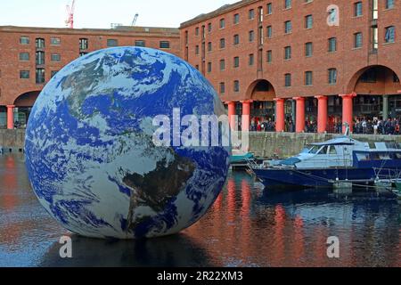 Luke Jerram Floating Earth kommt zum Royal Albert Dock in Liverpool, das an einem Abend bei Sonnenuntergang vor den Lagern des viktorianischen Hafens majestätisch aussieht Stockfoto