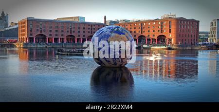 Luke Jerram Floating Earth kommt zum Royal Albert Dock in Liverpool, das an einem Abend bei Sonnenuntergang vor den Lagern des viktorianischen Hafens majestätisch aussieht Stockfoto