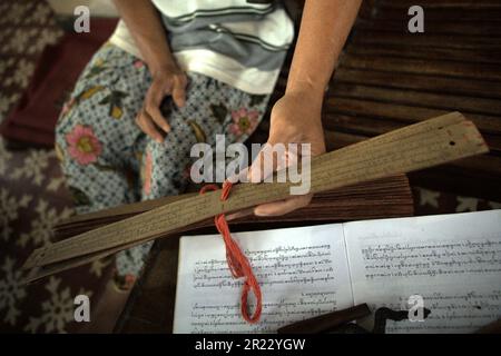 Ich Wayan EDI Wistara, ein balinesischer Handschrift-Praktizierender, zeigt eine Reihe von Palmenblättern, auf denen er alte balinesische Texte in seinem Haus in Karangasem, Bali, Indonesien, nachgeahmt hat. Einige Praktizierende kopieren alte balinesische Texte zurück auf neue Palmenblätter, um alte Traditionen zu bewahren. Stockfoto