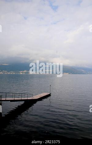 Interessantes Bild eines Piers ohne Personen, im Hintergrund können Sie die Berge und über ihnen eine dichte Schicht grauer und weißer Wolken sehen. Th Stockfoto