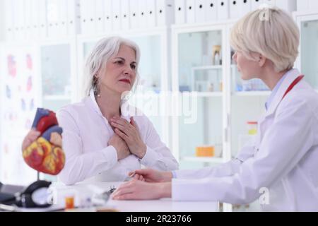 Eine Patientin legt die Hände auf die Brust und klagt über Schmerzen Stockfoto