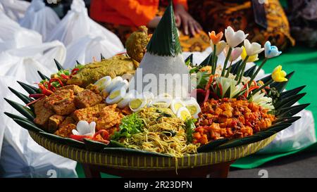 Nasi Tumpeng (Konusreis) serviert mit Urap-Uap (indonesischer Salat), gebratenem Hähnchen und Nudeln. Nasi-Tumpeng wird normalerweise auf Geburtstagspartys serviert Stockfoto