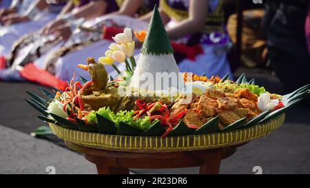 Nasi Tumpeng (Konusreis) serviert mit Urap-Uap (indonesischer Salat), gebratenem Hähnchen und Nudeln. Nasi-Tumpeng wird normalerweise auf Geburtstagspartys serviert Stockfoto